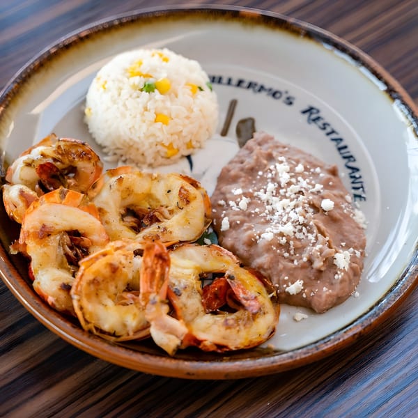 Guillermo's Restaurante plate with grilled shrimp, rice with corn and peas, and refried beans with cheese.