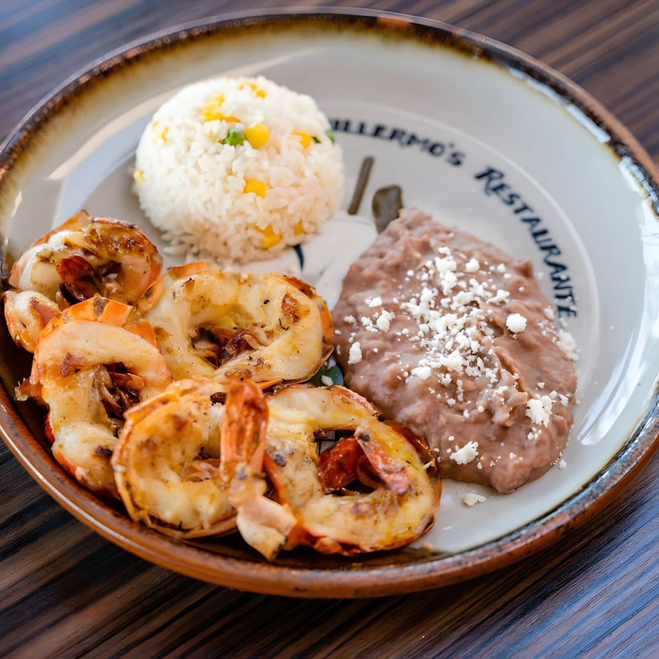 Guillermo's Restaurante plate with grilled shrimp, rice with corn and peas, and refried beans with cheese.