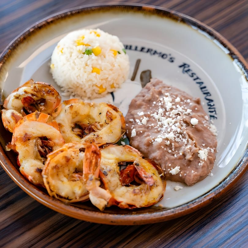 Guillermo's Restaurante plate with grilled shrimp, rice with corn and peas, and refried beans with cheese.