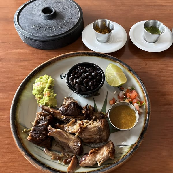 Guillermo's Restaurante carnitas plate with black beans, guacamole, pico de gallo, lime, and sauces.