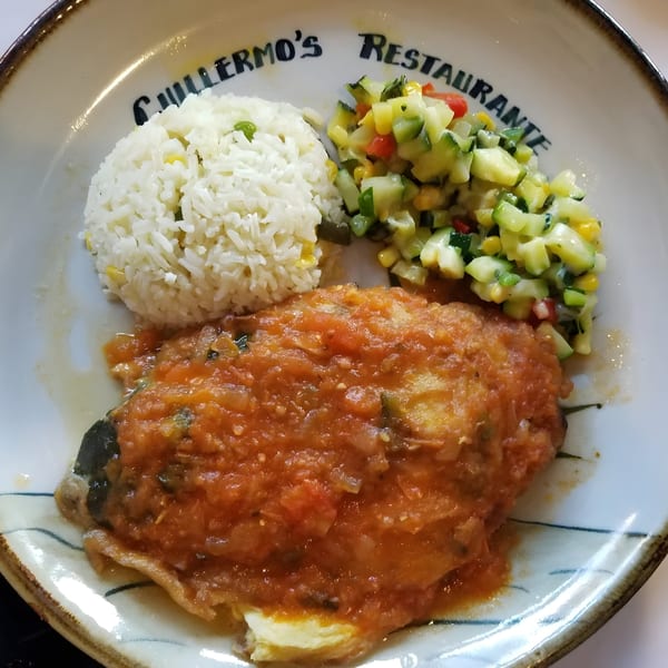 A Mexican dish with a chile relleno covered in red sauce, white rice, and a side of diced vegetables.
