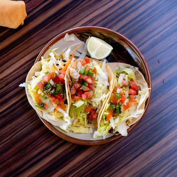 Three Guillermo's Restaurante tacos with shredded lettuce, pico de gallo, and a lime wedge.