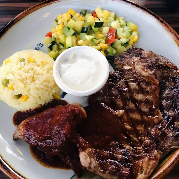 Guillermo's Mexican steak with rice, vegetable medley, and sour cream on a white plate.