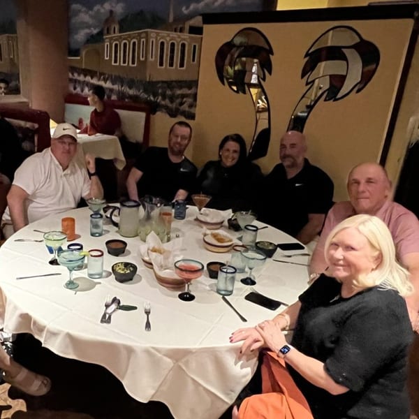 Six people enjoying drinks and appetizers around a white-clothed table at Guillermo's Restaurante.