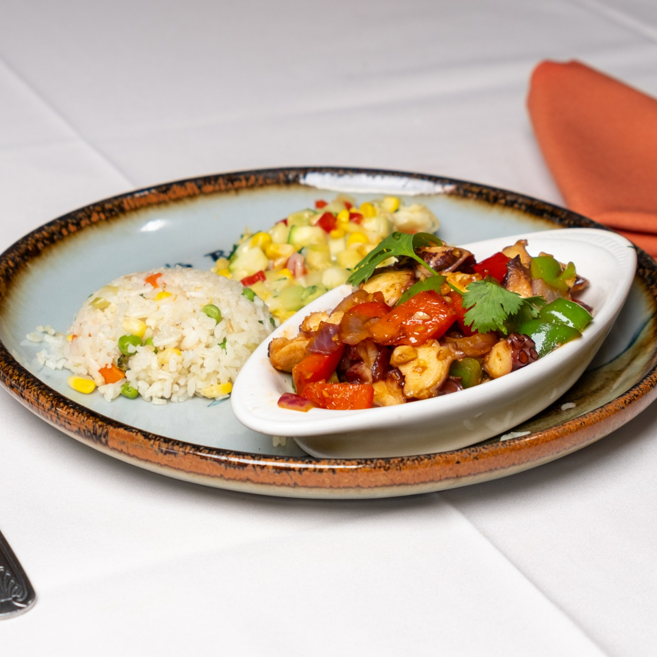Plated meal featuring vegetable fried rice, corn salad, and sautéed octopus with peppers and mushrooms.